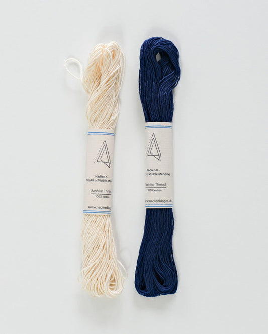 Two skeins of sashiko thread, one beige and one blue, on a white background.