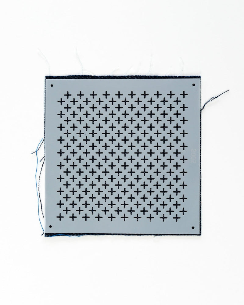 plastic cross-stitch stencil on an indigo background