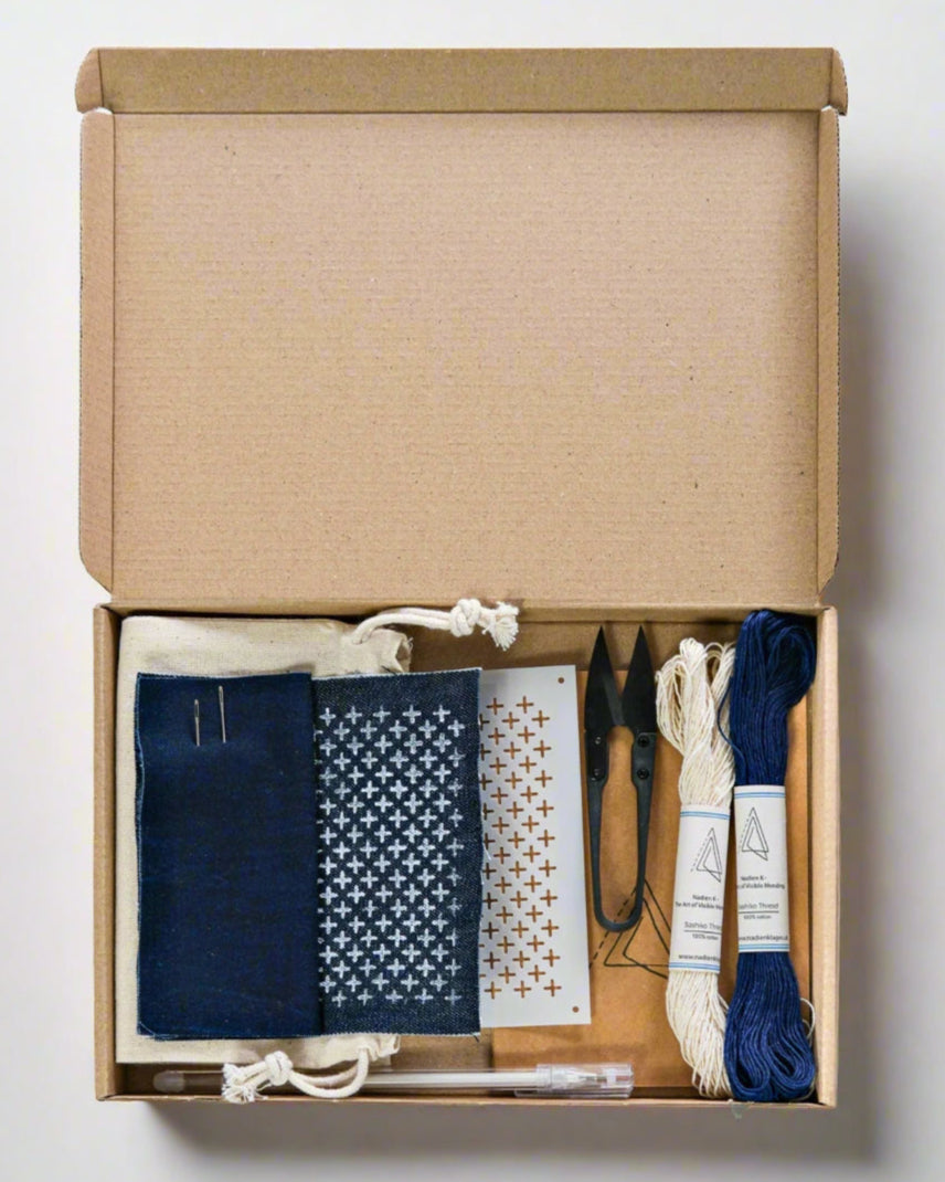 Cardboard box containing embroidery supplies on a white background