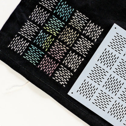 Two black and white sashiko stencils on a black fabric background