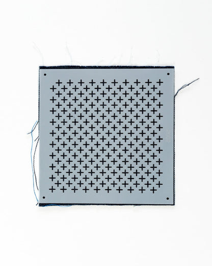 plastic cross-stitch stencil on an indigo background