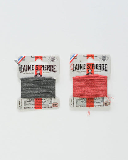 Two packages of Laine Spierre yarn, one grey and one coral, on a white background.