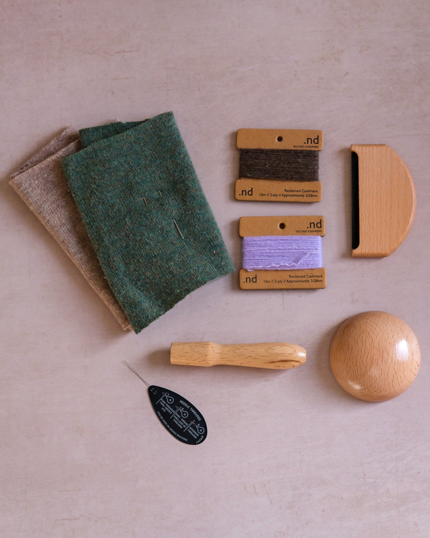 Cashmere mending kit containing a wooden darning mushroom, cashmere practice swatches, a wool comb, and cashmere mending wool